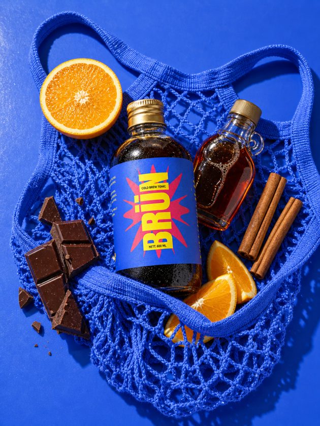 BRÜN bottle in a blue net bag with orange slices and chocolate