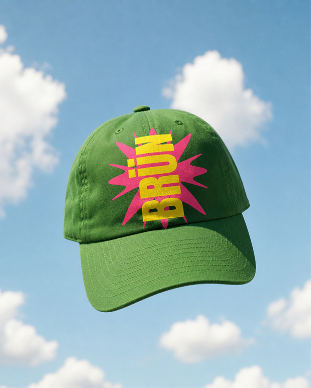 Green BRÜN baseball cap floating against a blue sky
