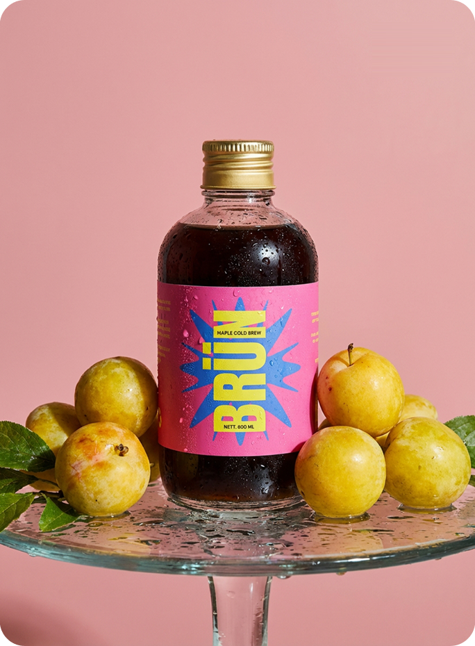 BRÜN Cold Brew Maple bottle with yellow plums on a glass stand