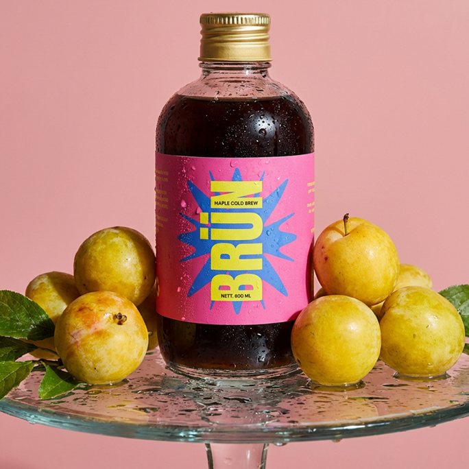 Maple bottle with yellow plums on a glass stand